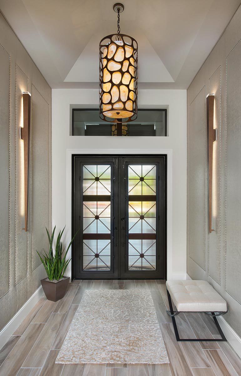 这个门厅设有引人注目的法式入口门和装饰有圆柱形吊灯的拱形天花板。