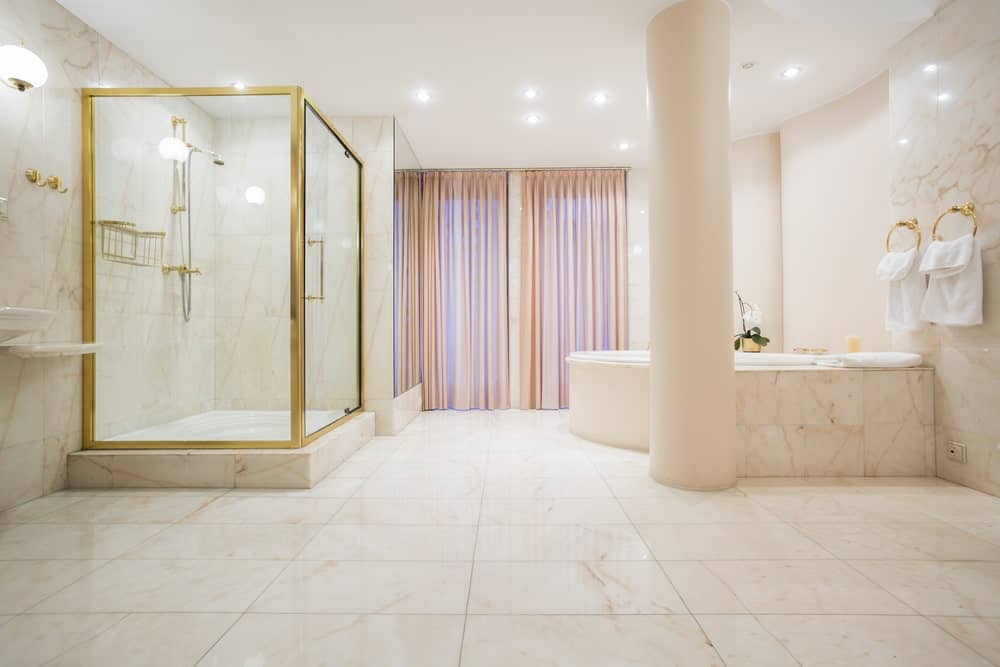 大的主浴室，可爱的大理石瓷砖地板和墙壁。角落的浴缸和淋浴都看起来很迷人。