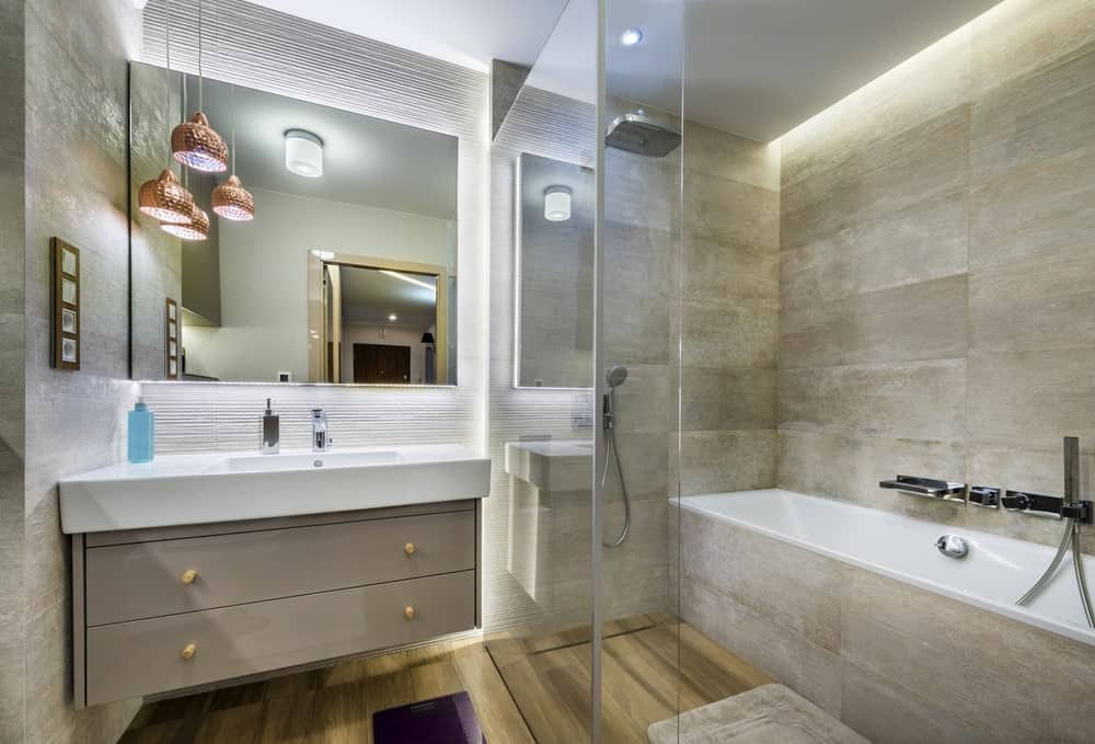这间主浴室拥有时尚的墙壁和地板。漂浮的梳妆台与浴缸和角落的淋浴器一起看起来很有档次。