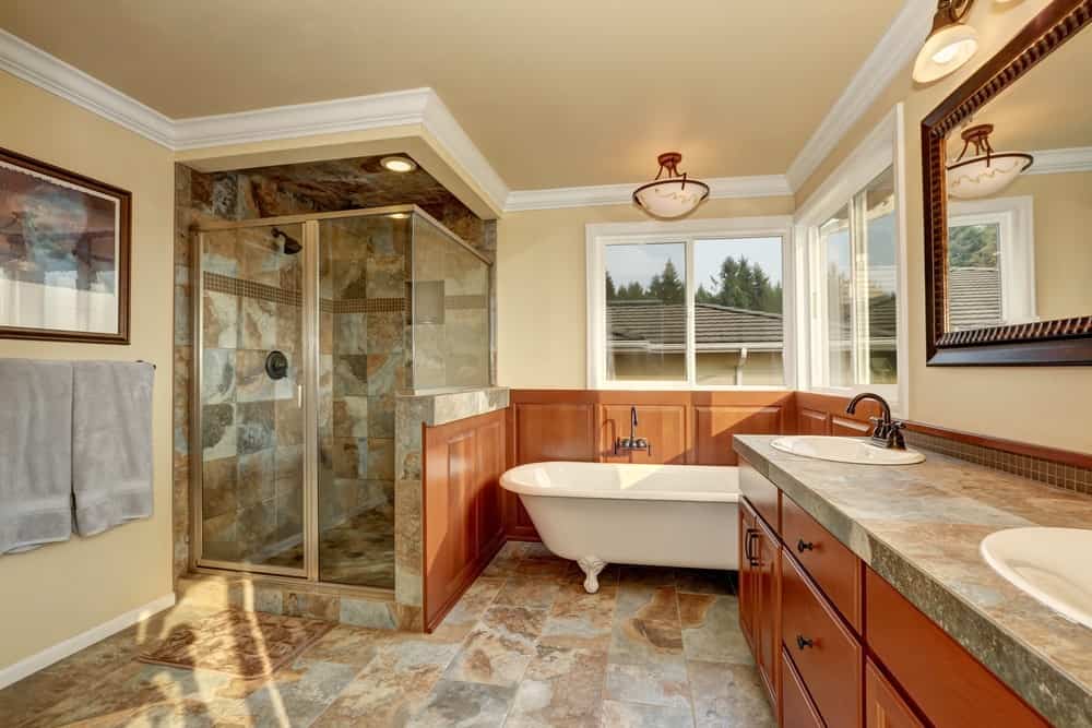 大型主浴室，带有角落淋浴，周围环绕着迷人的瓷砖墙壁和地板。角落里还有一个独立的浴缸。