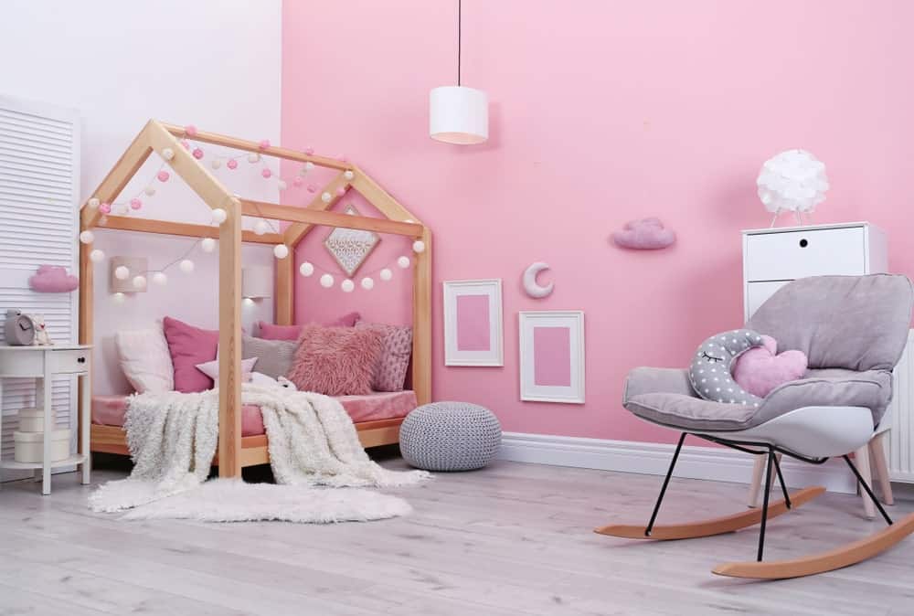 这个女孩的卧室拥有可爱的粉红色墙壁装饰。床看起来很漂亮，地板和房间的风格看起来很完美。