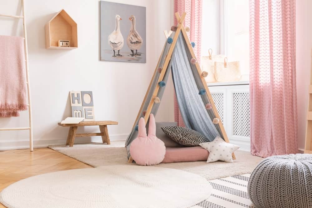 这个女孩的卧室提供了一个非常吸引人的床上白色地毯覆盖硬木地板。房间里的粉红色增添了一种可爱的感觉。