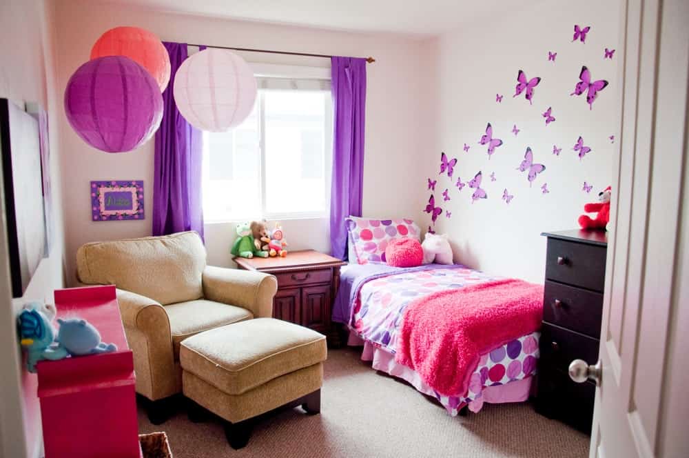 小女孩的卧室，墙上有可爱的蝴蝶图案。紫色的窗帘和地毯地板看起来都很高雅。