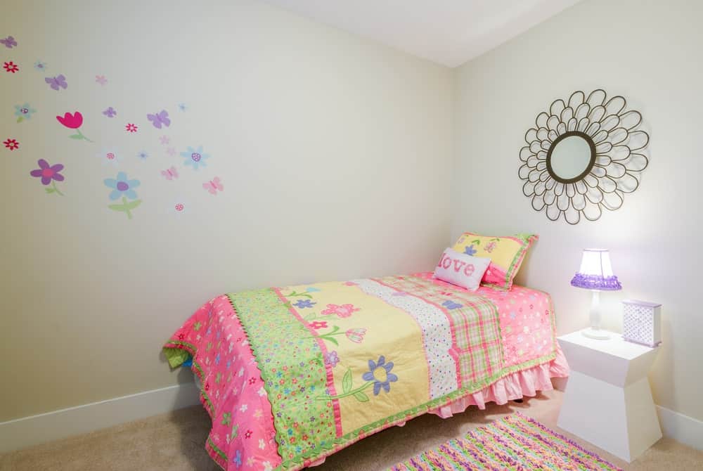 小女孩的卧室，可爱的墙壁设计和地毯地板，还有一个漂亮的边桌和婴儿灯。