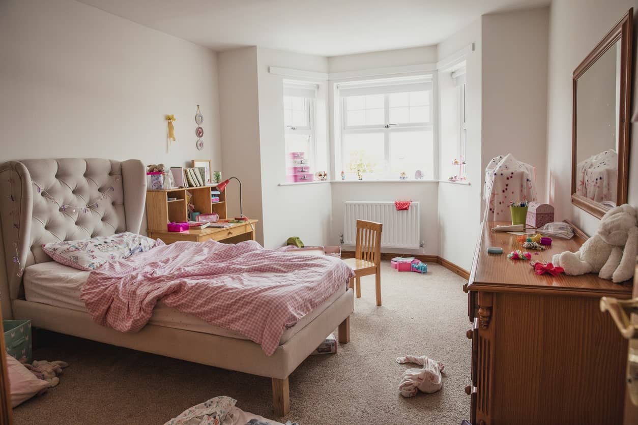 这个女孩的卧室是白色的墙壁和灰色的地毯地板。这张床看起来很豪华。床的一侧是木制的学习桌。