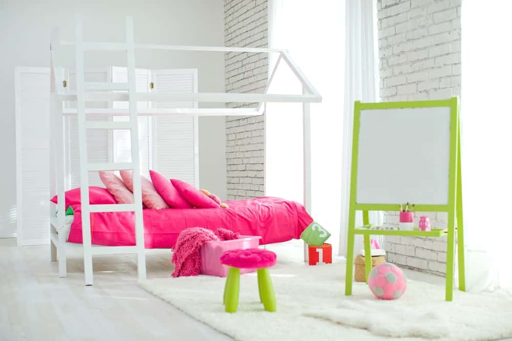 这个女孩的卧室以砖墙和硬木地板为特色，上面还有地毯。房间里的粉色基调看起来也很可爱。