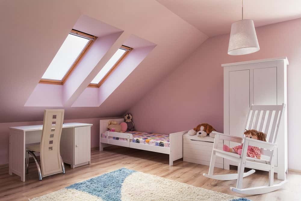 这个时髦的女孩卧室，粉红色的墙壁和棚顶。小床旁边有一张小书桌，都放在硬木地板上。