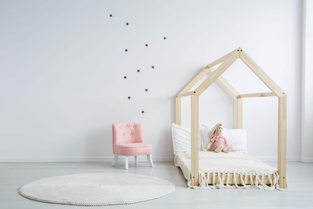 这间女孩卧室以星星设计的白色墙壁为特色。这张床看起来很时髦。硬木地板与墙壁和地毯很相配。