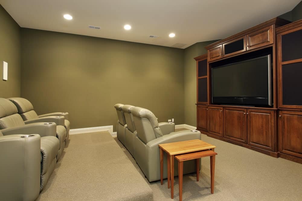 这个家庭影院拥有绿色和白色的墙壁。地毯地板和剧院座椅搭配起来很完美。