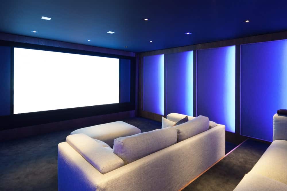 一个非常时尚的蓝色主题家庭影院，非常迷人的壁灯和天花板照明。地毯地板和这套沙发搭配起来很完美。
