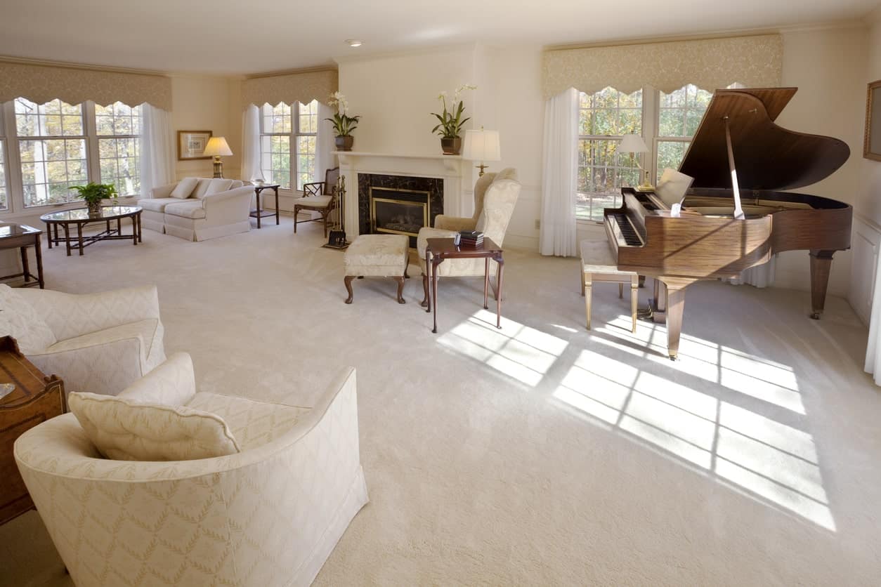 宽敞的正式客厅，提供优雅的座椅和壁炉，以及地毯地板上的大钢琴。