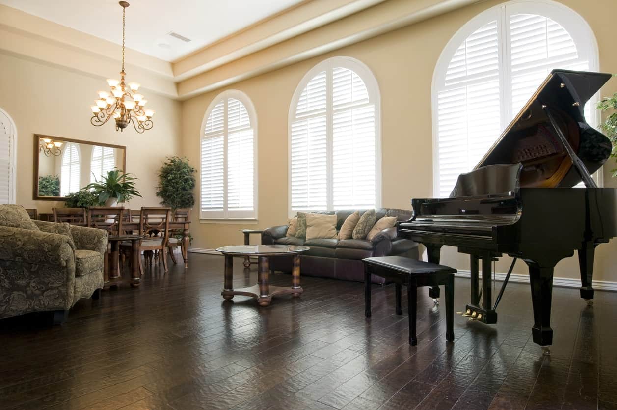 一个优雅的生活空间，配有优雅的沙发和硬木地板上的黑色钢琴，由华丽的枝形吊灯照明。
