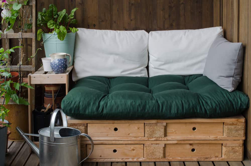 小庭院托盘沙发与白色枕头和绿色坐垫