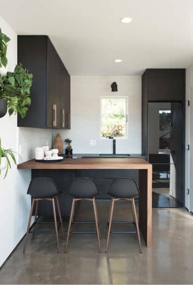 木色调的元素之间的平衡和黑色光滑的重点是北欧国家的厨房。光滑的黑色冰箱混合与黑沉区和橱柜安装在白墙以及黑色大便。