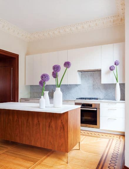 这个厨房的木制地板框架与模式,反映了模式框架的白色托盘天花板。挂在橱柜的简单的设计让他们看起来像一个固体结构挂在烹饪区。