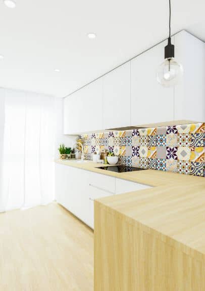 这个北欧国家的厨房的西班牙式风格与色彩斑斓的花纹砖填充墙挂白色的橱柜和l型厨房之间的半岛,木质台面,一直延伸到硬木地板。