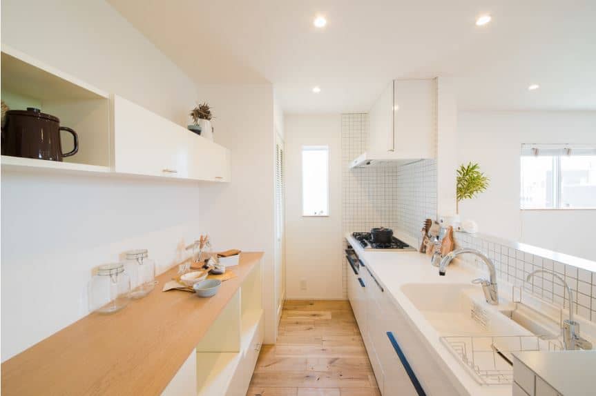 这hallway-like北欧国家的厨房有两个半岛的靠墙的对面。有一个木制台面和其他有一个白色的台面,洗手盆和烹饪区。