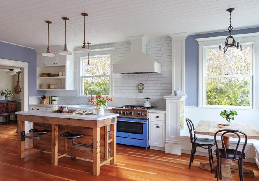 这间优雅的单墙厨房设有可爱的硬木地板和吊坠照明的白色木制天花板。在靠近窗户的角落里有一个小的用餐角落。