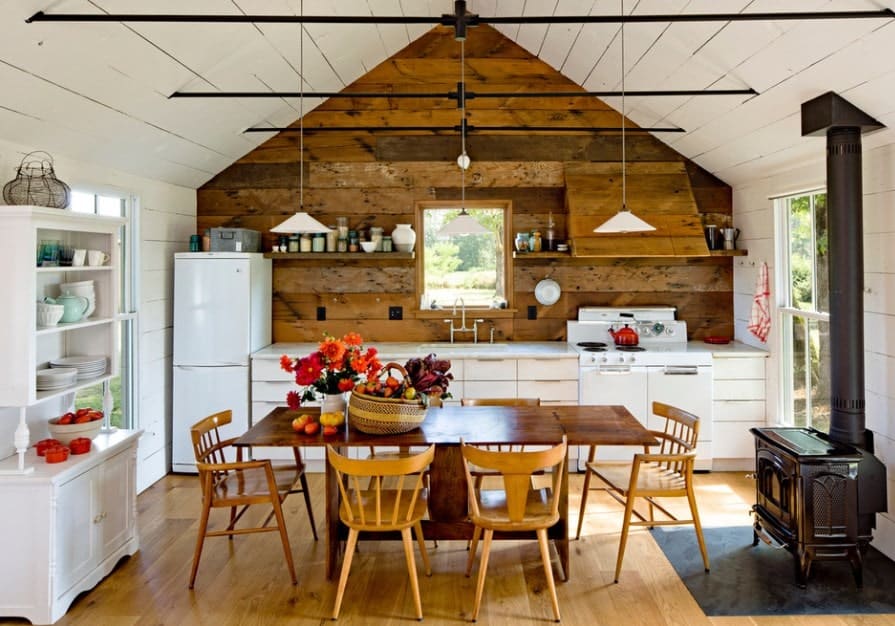 单墙厨房，白色柜台和台面设置在硬木地板上，与由吊灯照亮的木制餐桌相匹配。