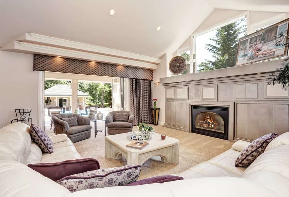一个大的优雅的正式起居空间，一个优雅的沙发设置在可爱的地毯地板上。壁炉看起来很时髦。