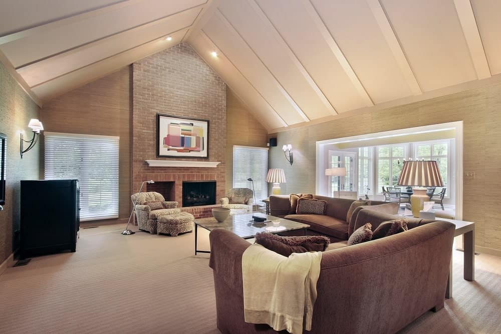 优雅的正式客厅，优雅的地毯地板上有一个漂亮的沙发。带有砖墙的壁炉延伸到拱形天花板，看起来也非常时尚。