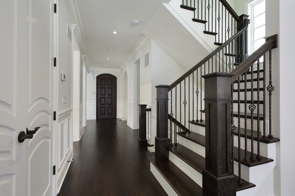 这优雅的大厅是由白色的木质墙壁,护墙板,白色木门和白色的天花板与凹式灯。这是进一步改善其黑暗的实木地板相比,铁艺栏杆的木制楼梯扶手楼梯。