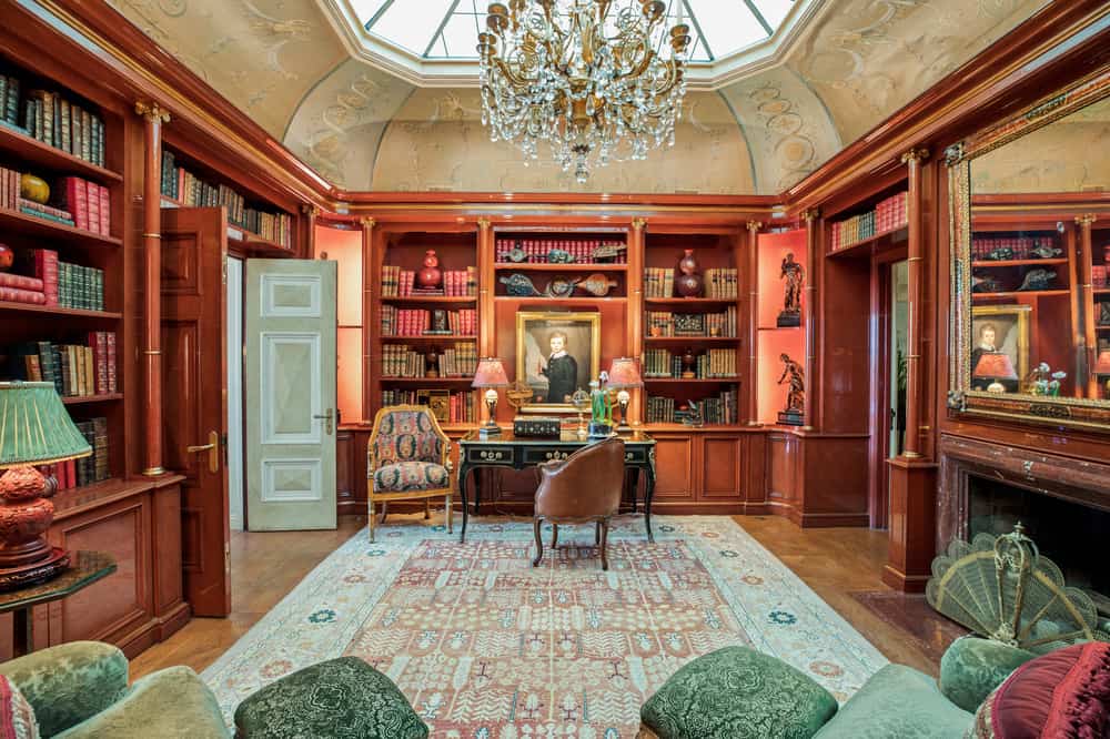 这是一个很好的老式家庭图书馆的例子，它是由丰富的木材、夸张的枝形吊灯、华丽的桌子、壁炉和塞满家具定制的。
