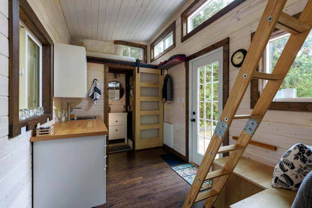 一个小木屋的内部主要生活空间，有厨房区域和两间阁楼卧室，可以通过梯子进入。