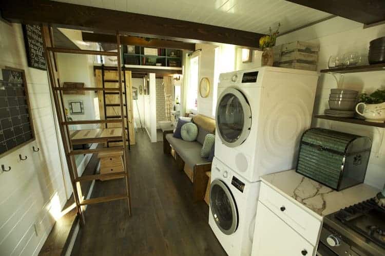 可堆积的洗衣机和烘干机在一个小房子里面有黑暗的木地板。
