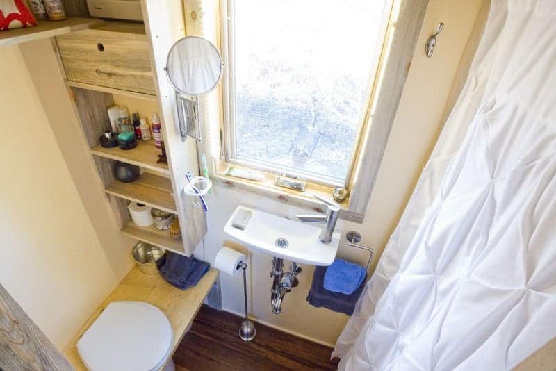 简单的小房子浴室，带长凳厕所，小浮动水槽，窗户和淋浴。