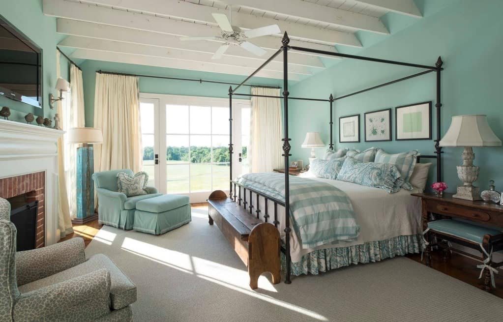 一个优雅的主卧室，整个房间都是蓝绿色的阴影。硬木地板上铺着一块传统的大地毯。