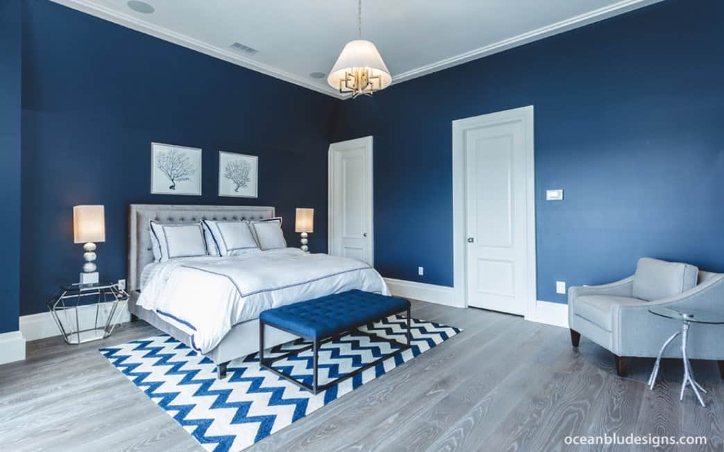 宽敞的主卧室，时尚的蓝色墙壁和硬木地板，以及时尚的床和座位。