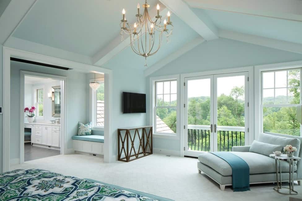 一个大的主卧室，浅蓝色的墙壁和白色的地毯地板，上面有迷人的绿色地毯。