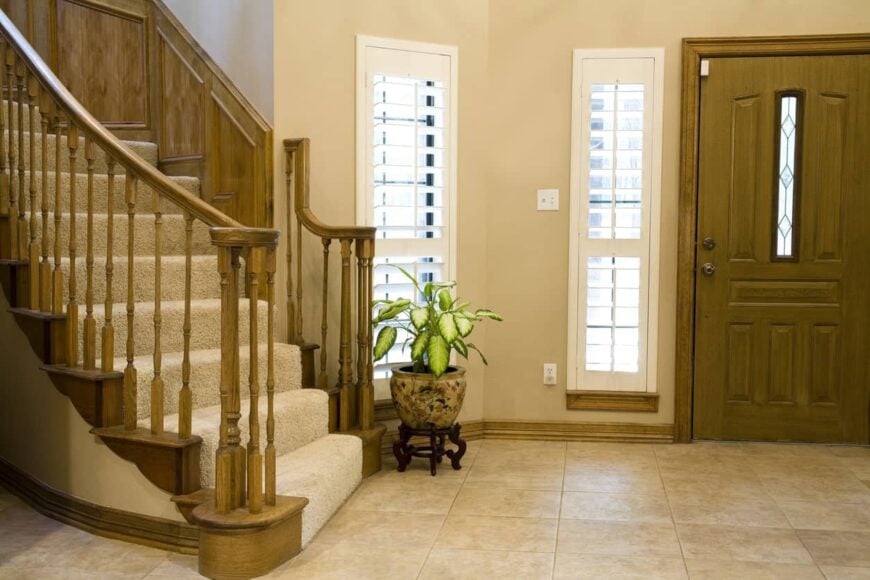 一个铺着瓷砖地板的小入口和铺着地毯的楼梯。它还以木制栏杆为特色。