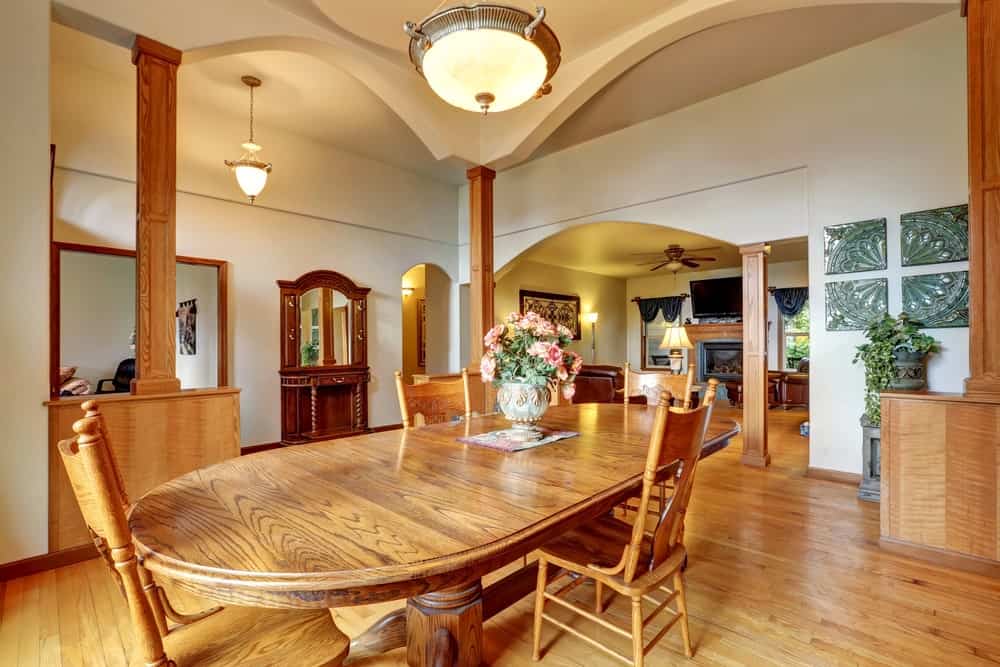 一个优雅的椭圆形餐桌，由一个华丽的吊坠照明设置在家里的高天花板。