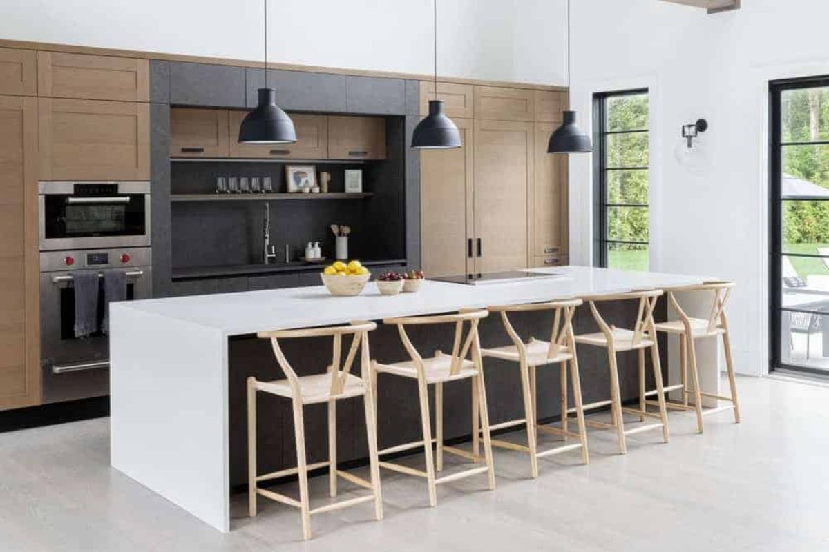住宅的特色是一个带有棕色橱柜的单墙厨房，以及一个由吊灯照亮的白色早餐吧台台面。