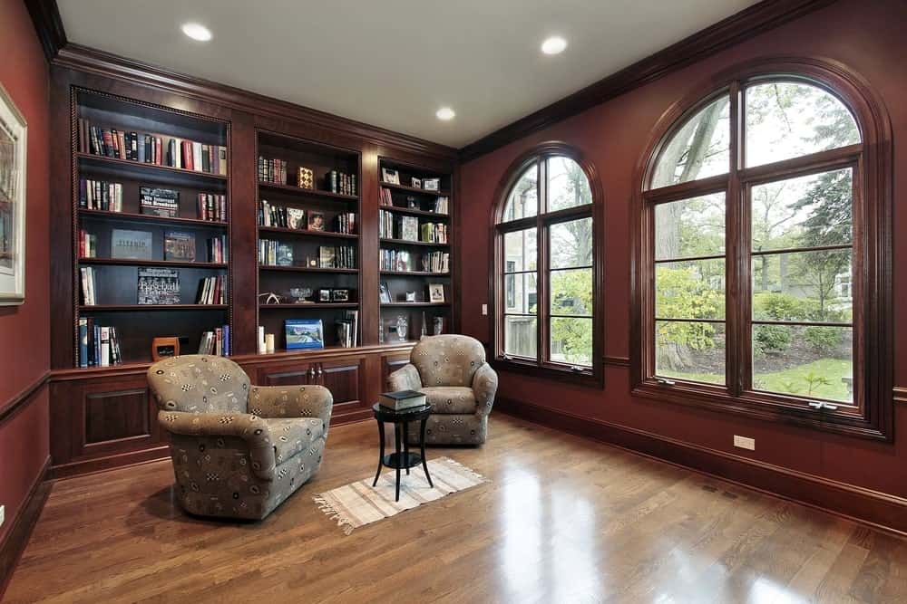 一个优雅的家庭图书馆，有优雅的座椅和硬木地板上的咖啡桌。墙壁和内置的架子看起来很完美。
