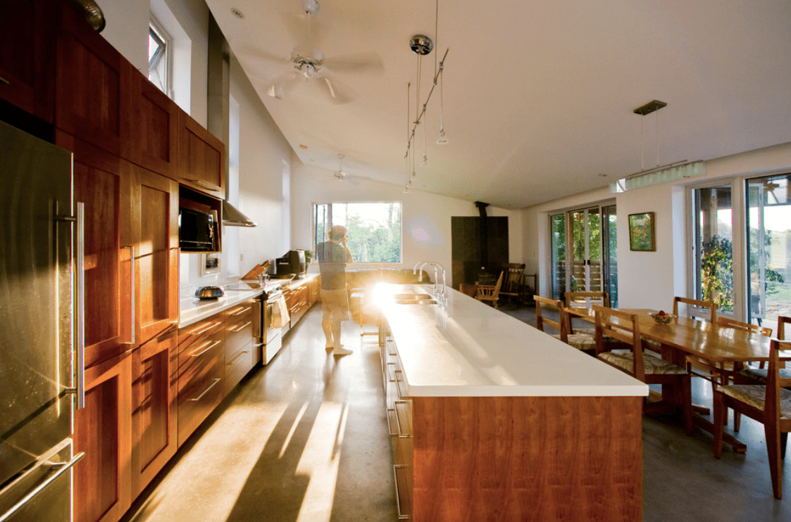 餐厅厨房设有中央岛和厨房柜台的白色台面。中间的岛台旁边有一张长方形的餐桌。