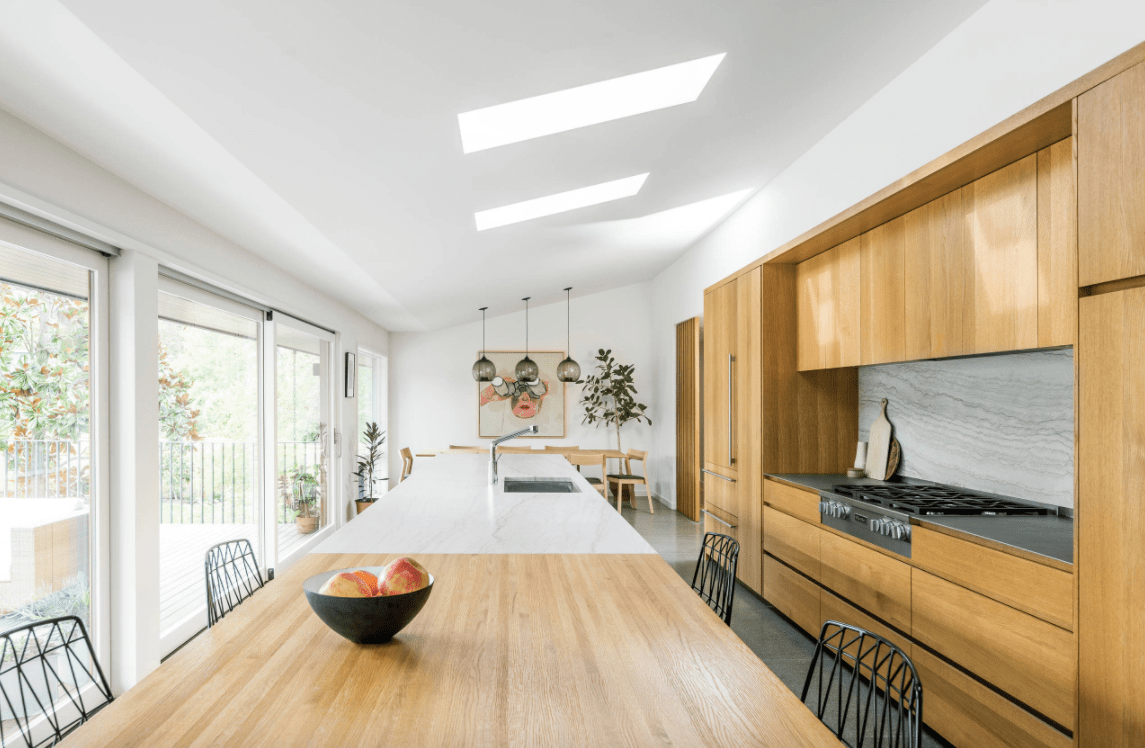 一个优雅的厨房，设有带天窗的白色棚顶。厨房以胡桃木装饰的橱柜和厨房柜台为特色。