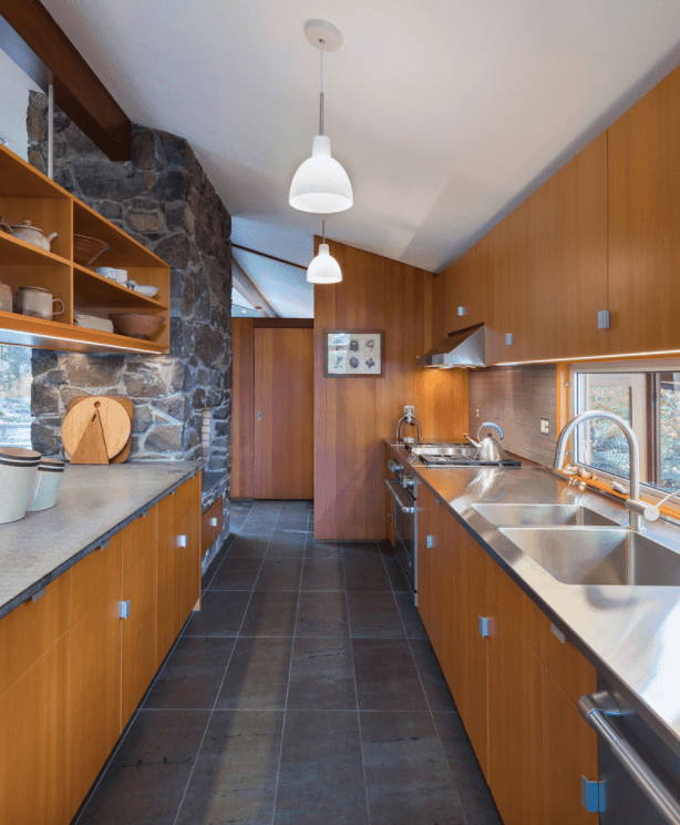 这间厨房设有时尚的黑色地板和白色棚顶，由吊灯照明。