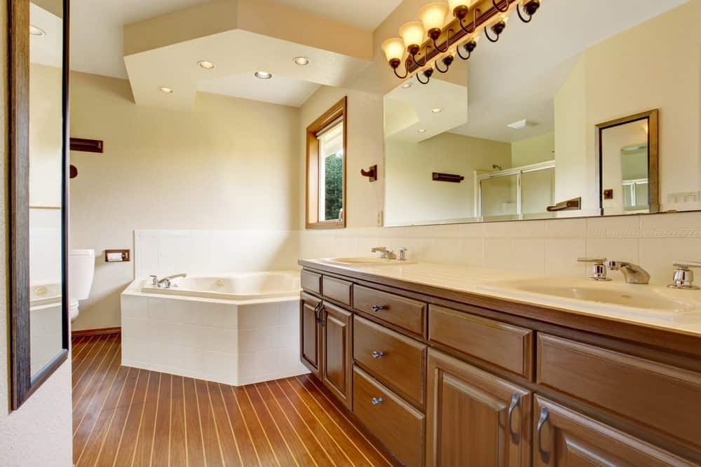 大型主浴室，带一个大角落浴缸和一个双水槽，以及硬木地板。