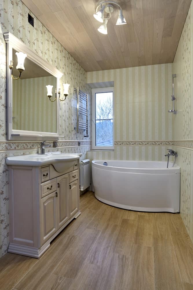主浴室有优雅的墙壁和硬木地板，还有一个大的角落浴缸和侧面的一个洗手池。