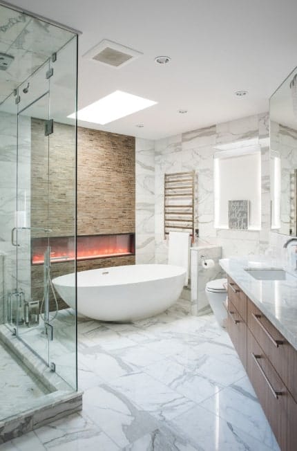 一个时尚的主浴室，大理石瓷砖地板和墙壁。这间房间还设有一个独立浴缸，靠近大型现代化壁炉。房内有一间步入式淋浴间和一个带大理石台面的洗涤台。