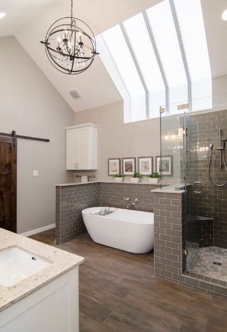 宽敞的主浴室，棕色硬木地板上设有独立浴缸。还有一间步入式淋浴间。