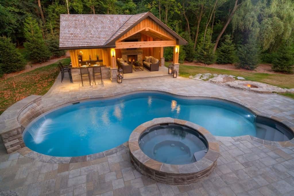 肾形游泳池设有一个优雅的池畔住宅，提供酒吧区和一个带壁炉和电视的起居空间。