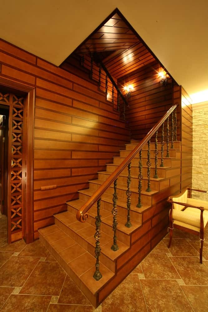 家的条目与乡村风格楼梯瓷砖地板和有吸引力的墙壁,迷人的墙灯点亮。