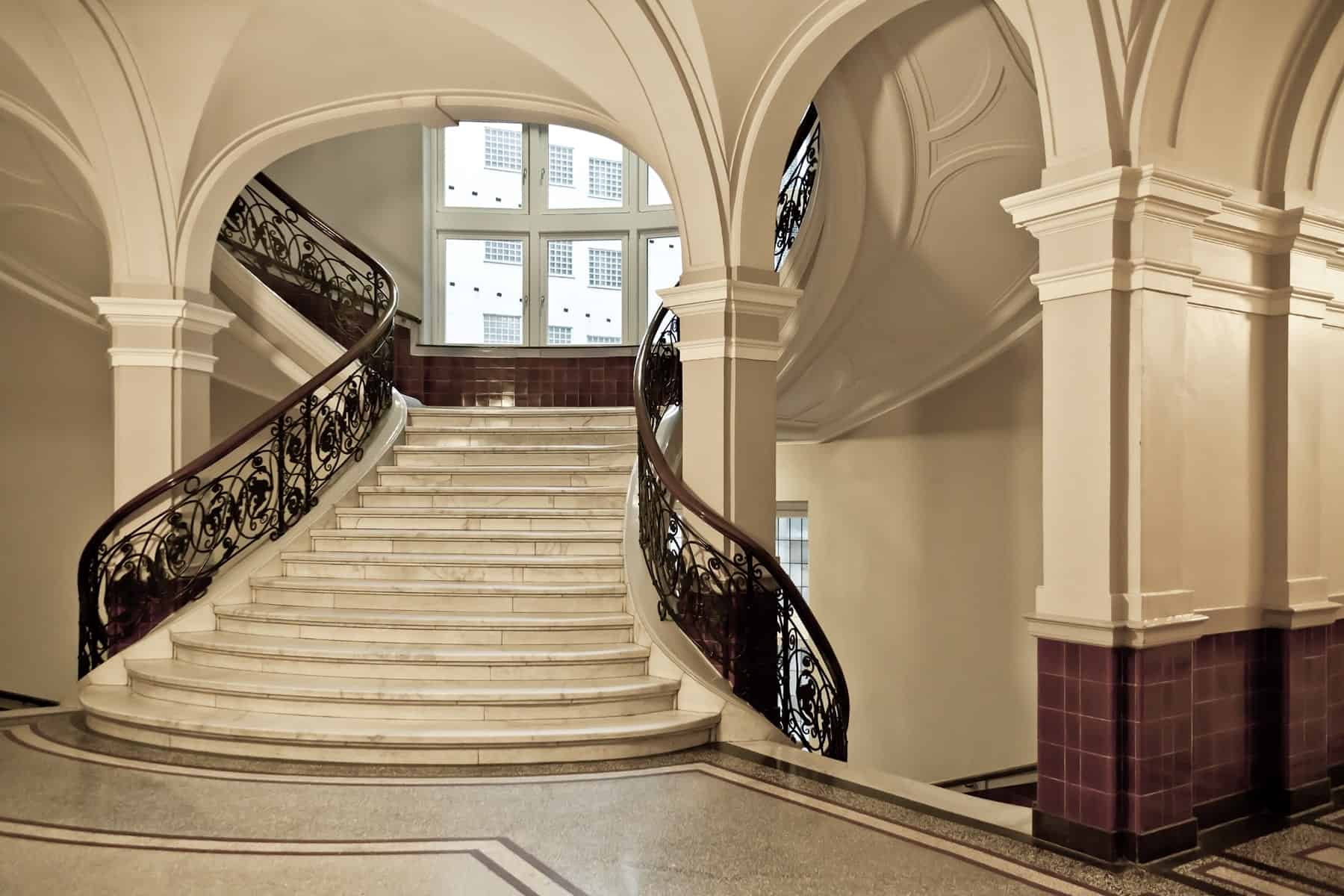 一个宏伟的门厅设有一个分体式楼梯，配有优雅的大理石瓷砖地板和优雅的栏杆。