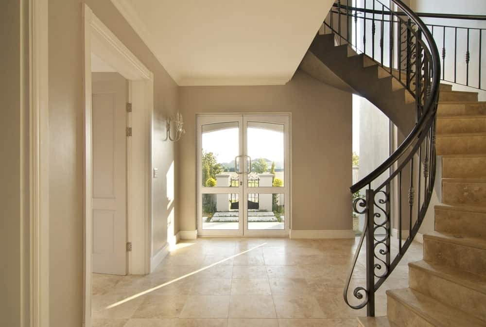 家里条目与环形楼梯,米色的瓷砖地板,看起来很潇洒。
