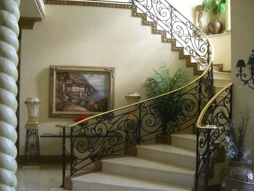 楼梯上铺着白色的瓷砖地板和黑色的栏杆，还有镀金的扶手。