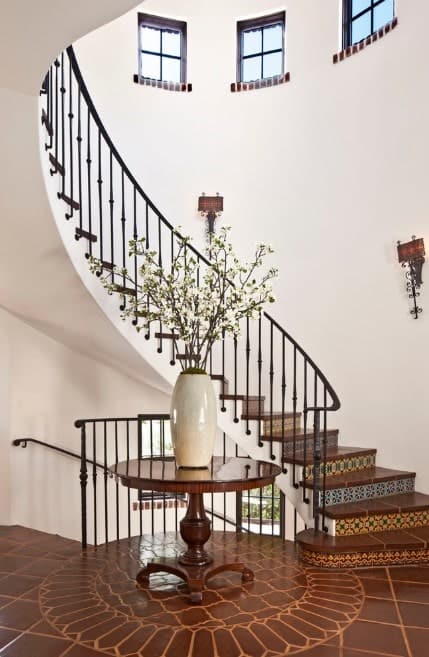 华丽的弧形楼梯，棕色瓷砖地板被白色墙壁包围，并由墙壁照明。